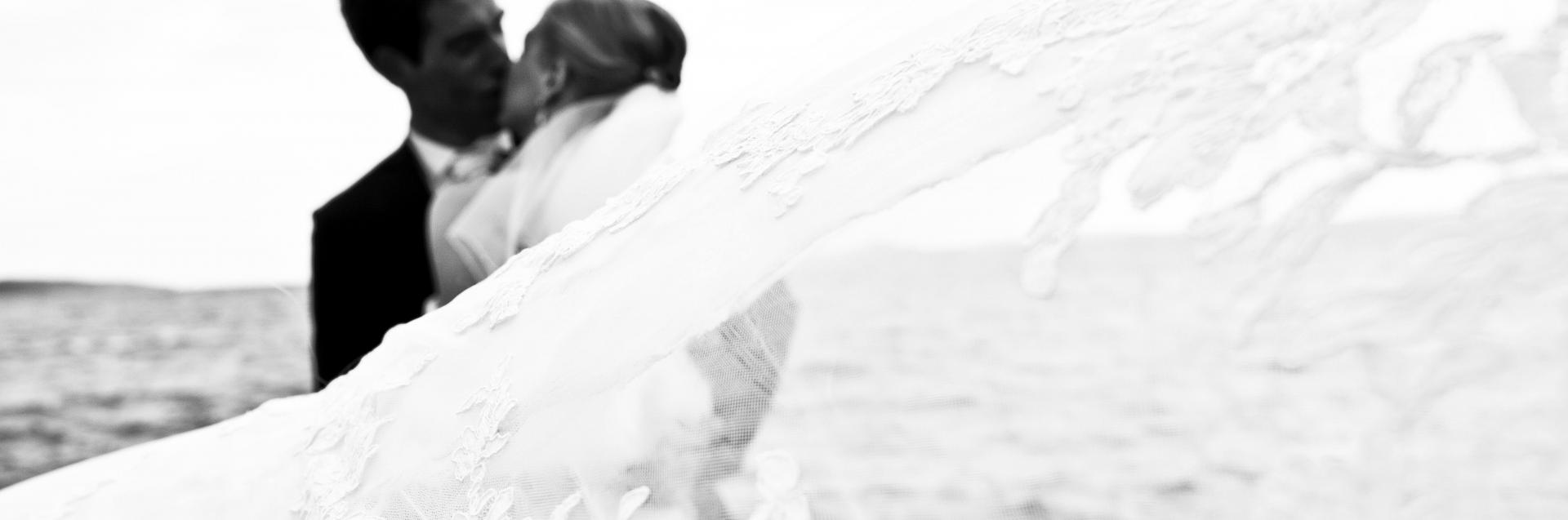 bride in ballgown and groom kissing on beach